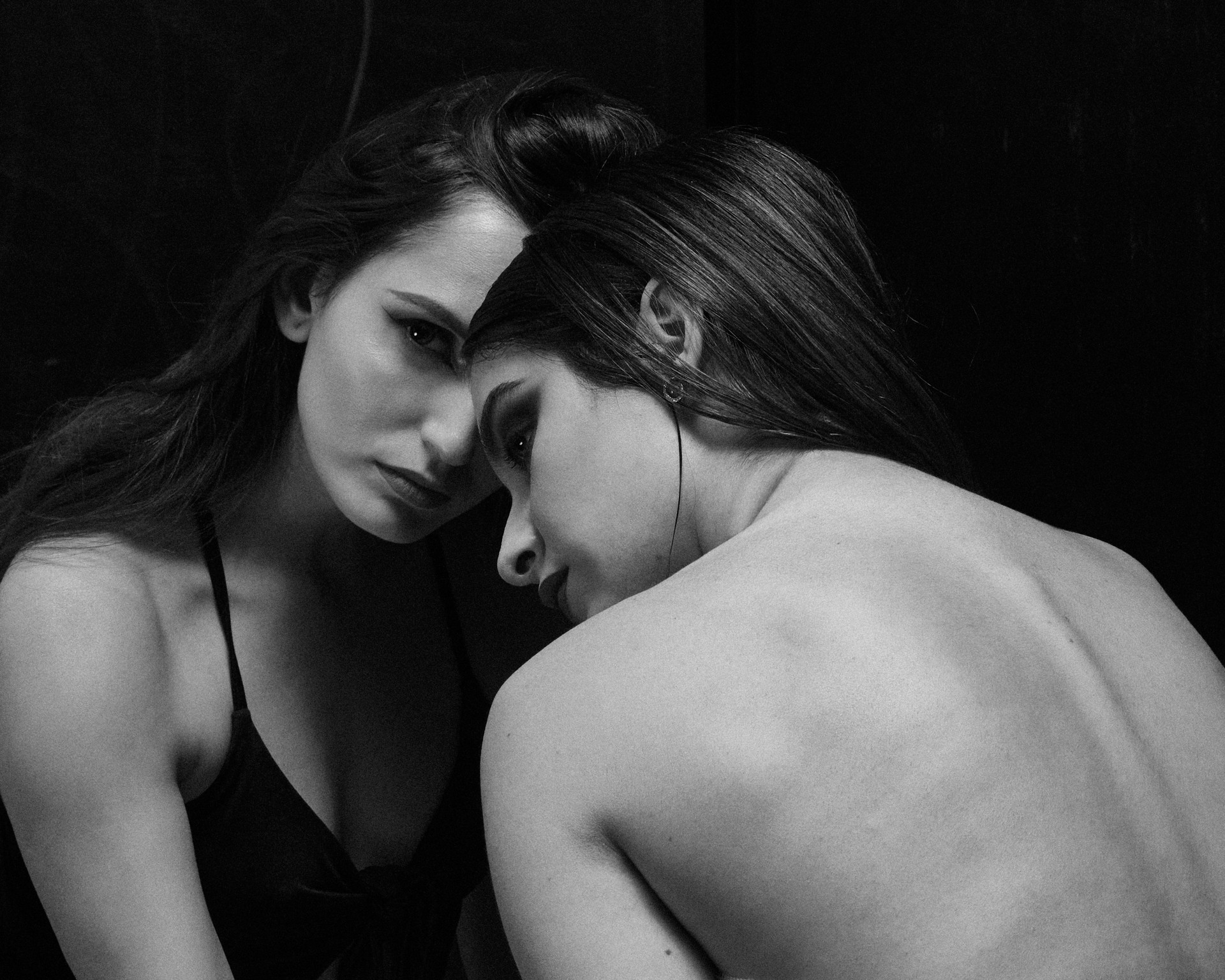 An absence series figure holds a charged, unresolved presence in darkness.